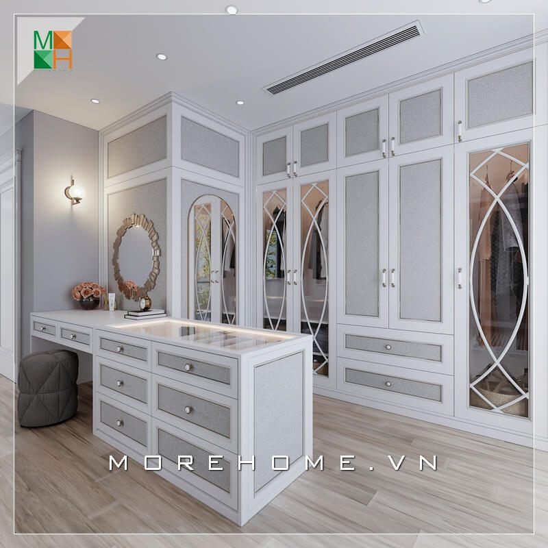 Mẫu phòng thay đồ đẹp cho biệt thự, chung cư cao cấp mang phong cách tân cổ điển, sử dụng gam màu trắng xám làm chủ đạo với hệ tủ âm tường kịch trần và đảo phụ kiện kết hợp bàn trang điểm, giúp không gian thử đồ của gia chủ trở nên gọn gàng nhưng cũng không kém phần sang trọng, đẳng cấp